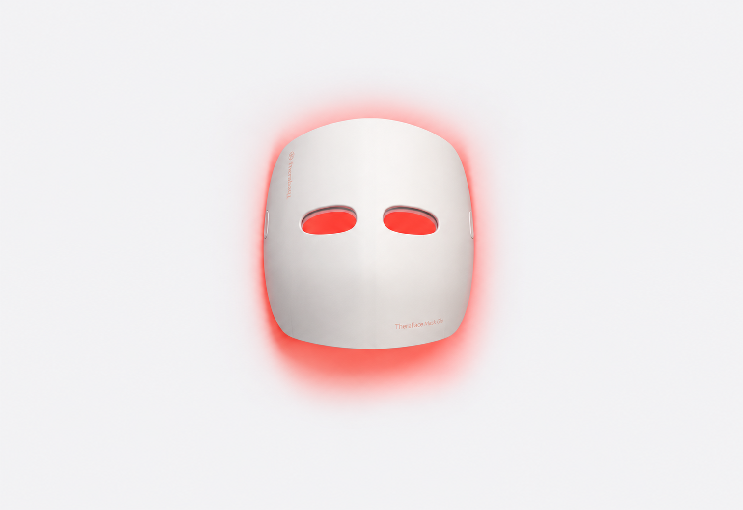 Therabody TheraFace Mask Glo LED facial mask glowing red on a soft light-gray background